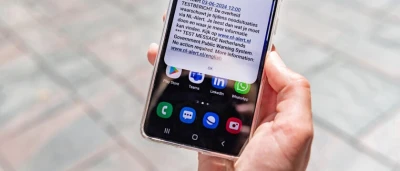 Een hand houdt een smartphone met een melding op een straat met stenen.