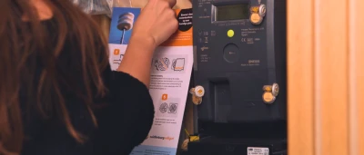 Jonge dame hangt meterkastkaart op in meterkast