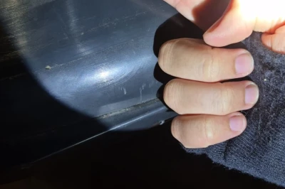 Een hand met een opgestoken vinger, verlicht door een zaklamp, wijst naar een auto.