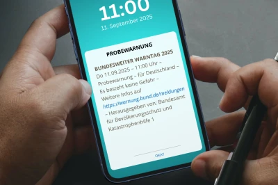 Een hand houdt een smartphone met een notificatie en de tijd 11:00 op het scherm.