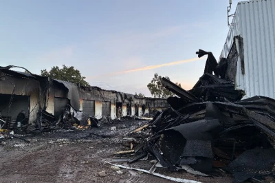 Verwoeste gebouwen na een brand, met roet en puin verspreid over de grond.
