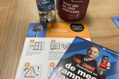 Een tafel met een fles water, een paarse verpakking en informatiefolders.