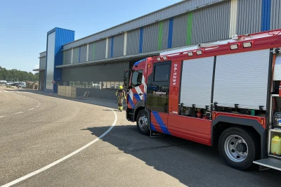 Brandweerwagen geparkeerd bij een gebouw, helder blauwe lucht op de achtergrond.