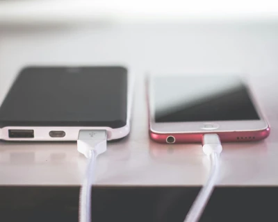 Twee smartphones met oplaadsnoeren aangesloten op een tafel.