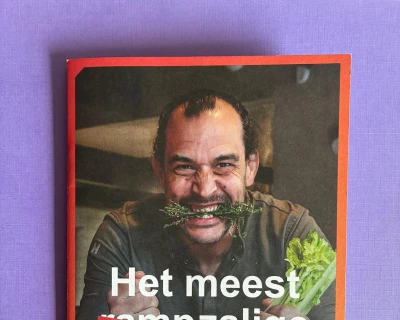 Een persoon glimlacht breed met groenten in handen op een kookboekomslag.